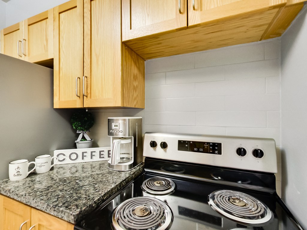 A coffee maker is on a counter next to a stove.