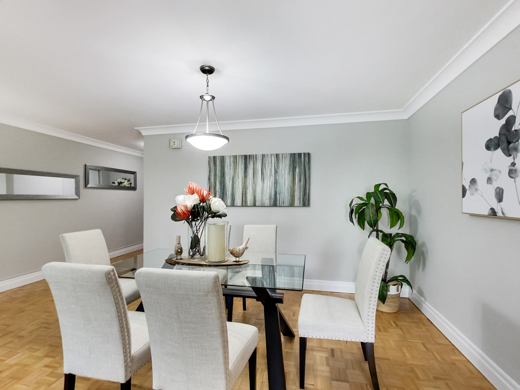 A dining room with a glass table and white chairs.