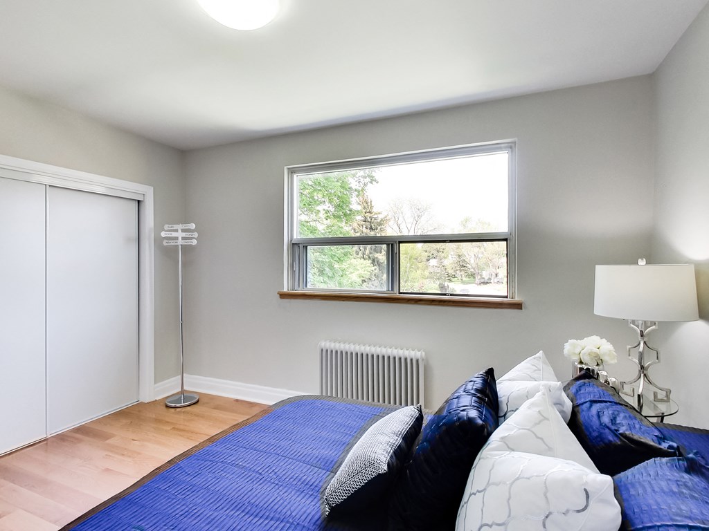 A bedroom with a bed, pillows, a lamp, and a window.