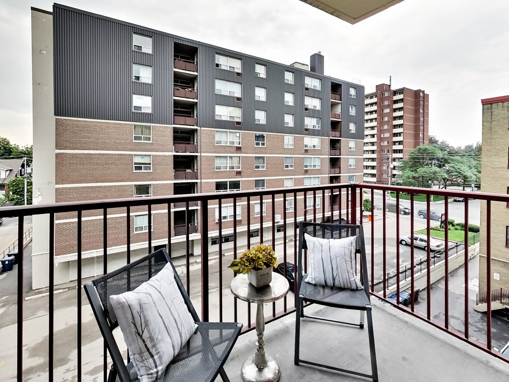 an apartment balcony with two chairs and a table with flowers