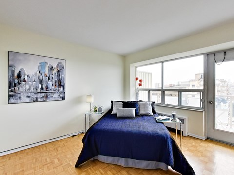 A bedroom with a large bed and a cityscape picture on the wall.