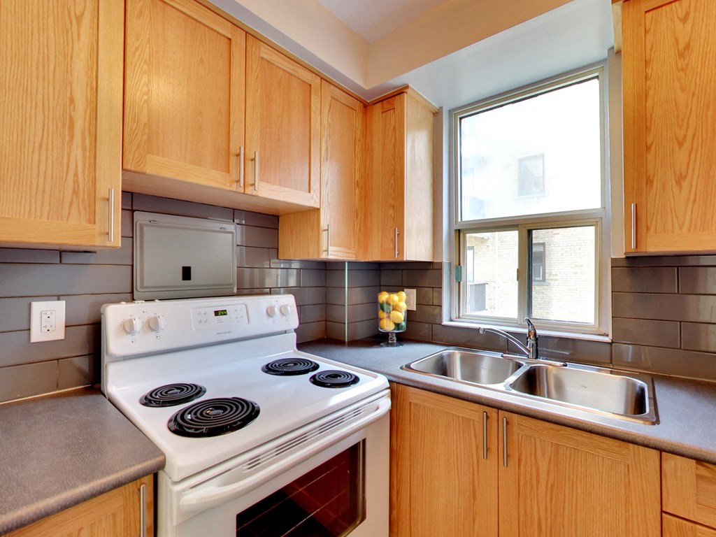 a kitchen with wood cabinets and white appliances and a window