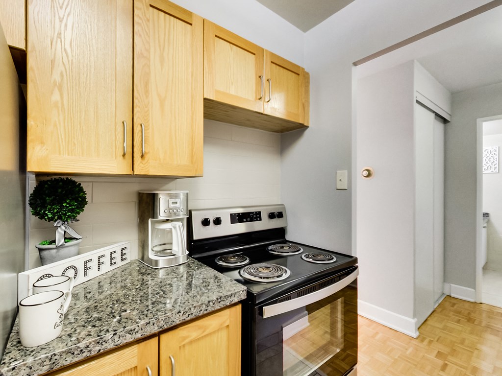 A kitchen with a stove top oven and wooden cabinets.