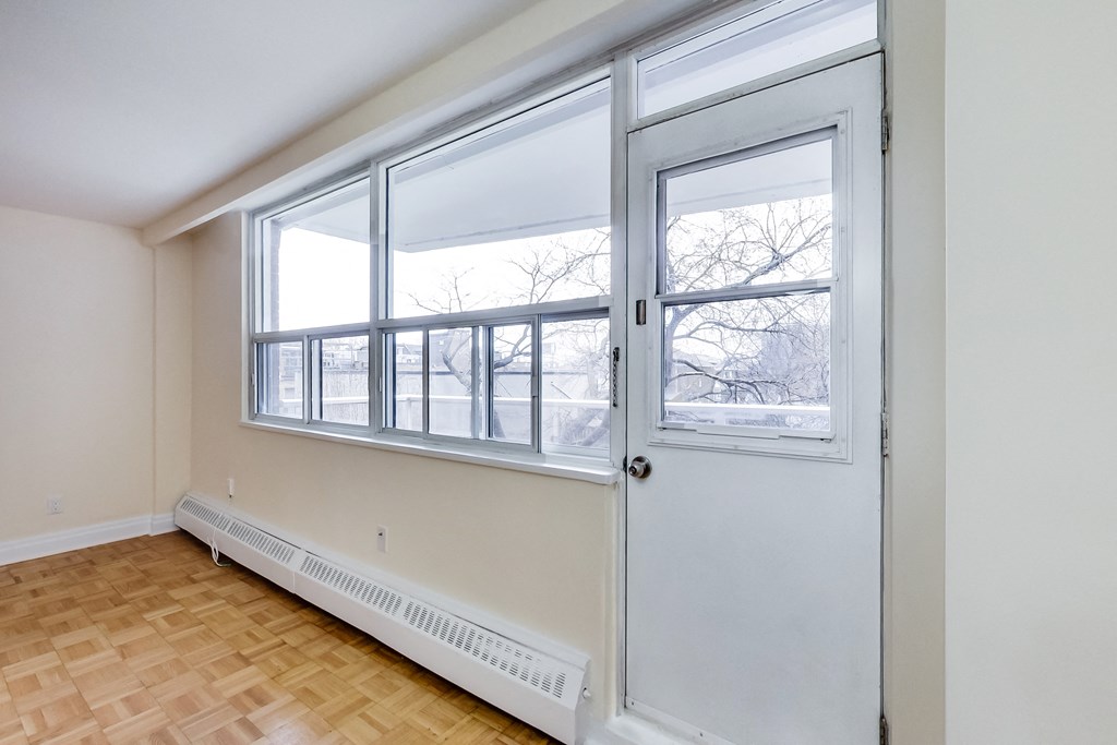 A room with a white door and a window with a view of a snowy landscape.