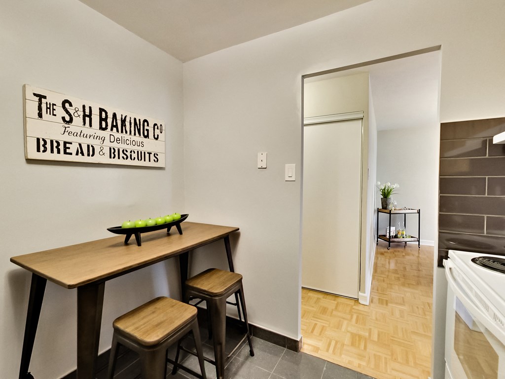 A bakery with a wooden table and stools is set up in a room.