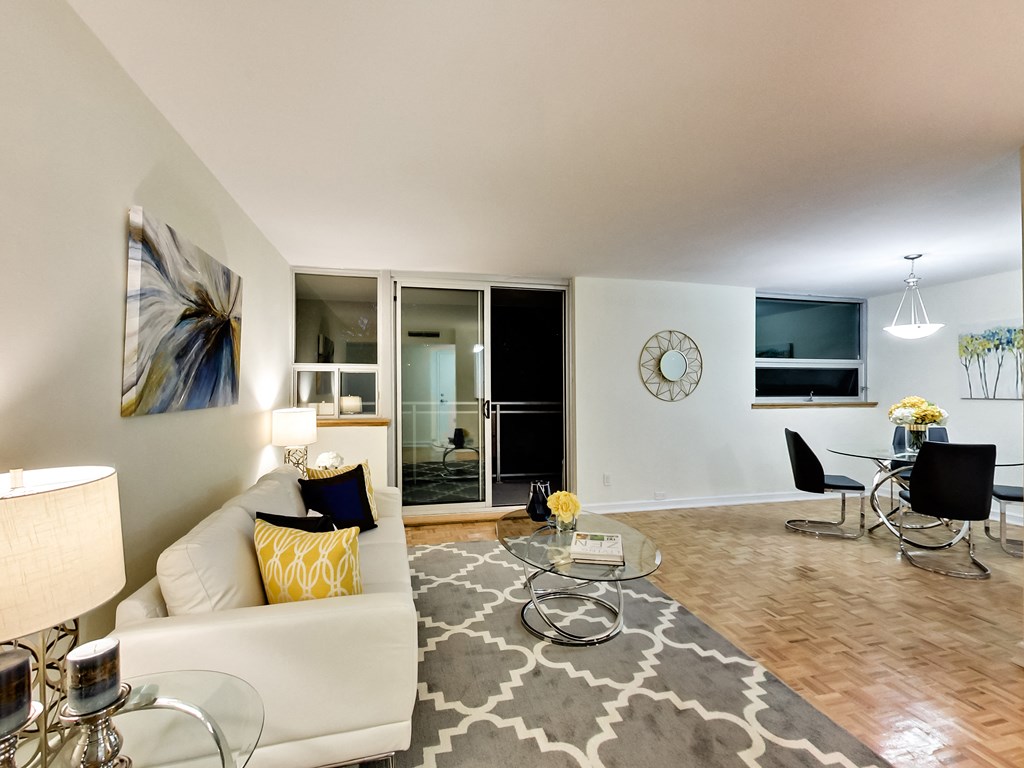 A living room with a white couch and a grey rug.