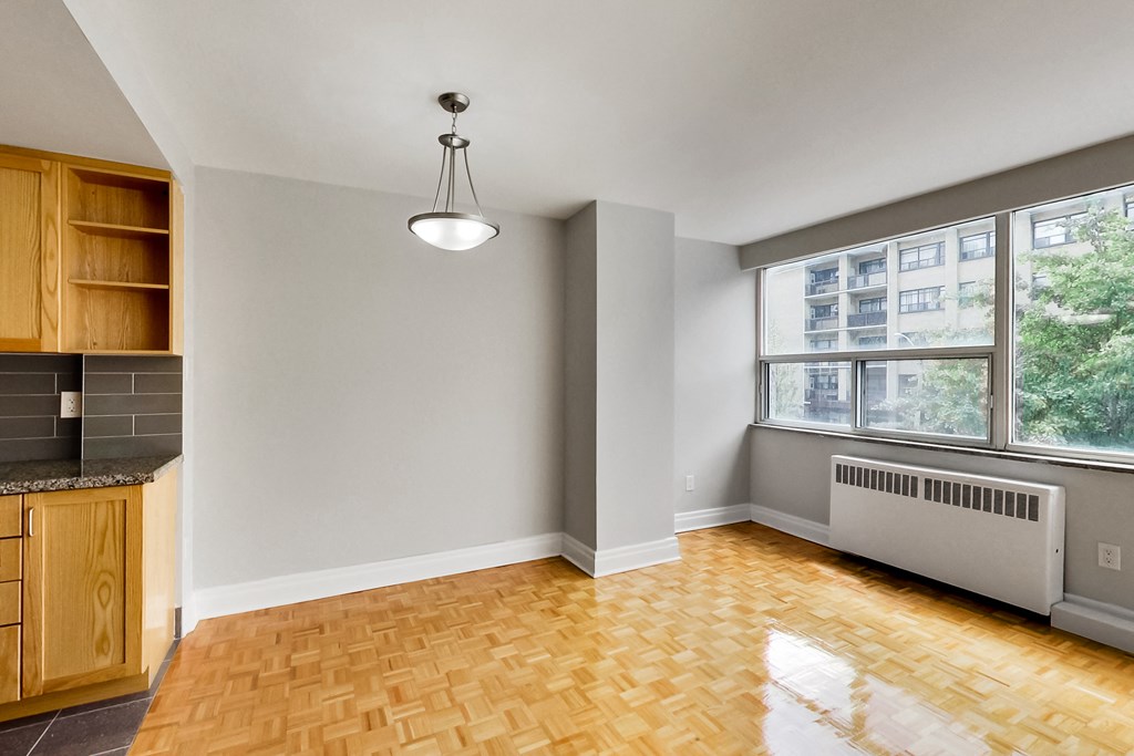 an empty living room with a kitchen and a large window