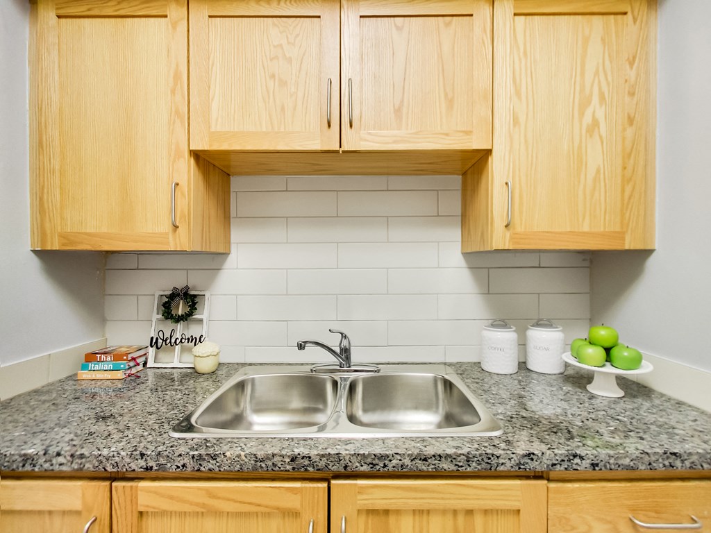 A kitchen with a granite countertop and wooden cabinets.