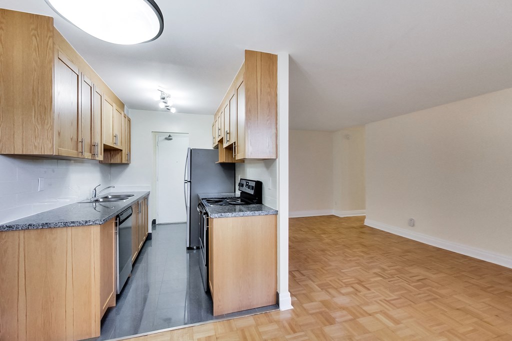 A kitchen with wooden cabinets and a black fridge.