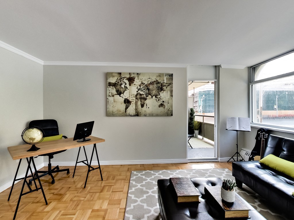 A room with a wooden desk and a black couch.