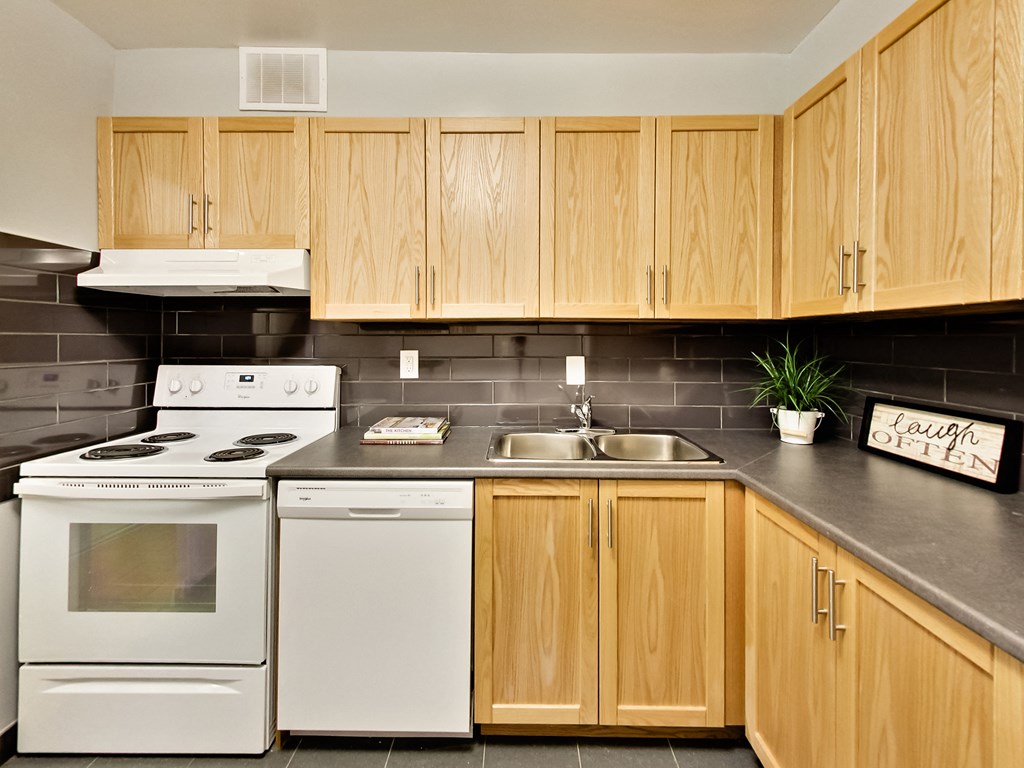 A kitchen with wooden cabinets and a white stove top oven.