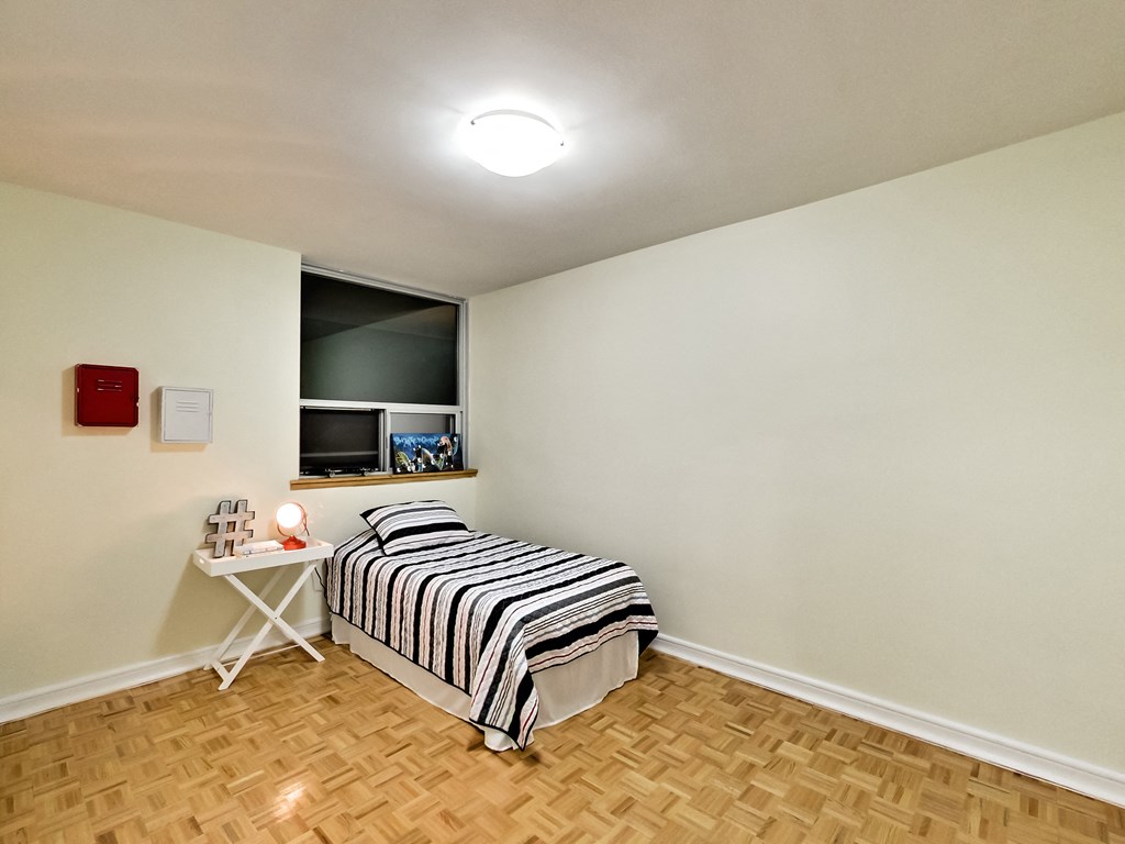 A bedroom with a bed, a table, and a window.