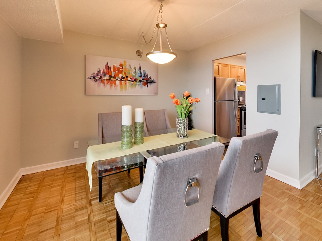 a dining room with a glass table and chairs and a kitchen with a refrigerator