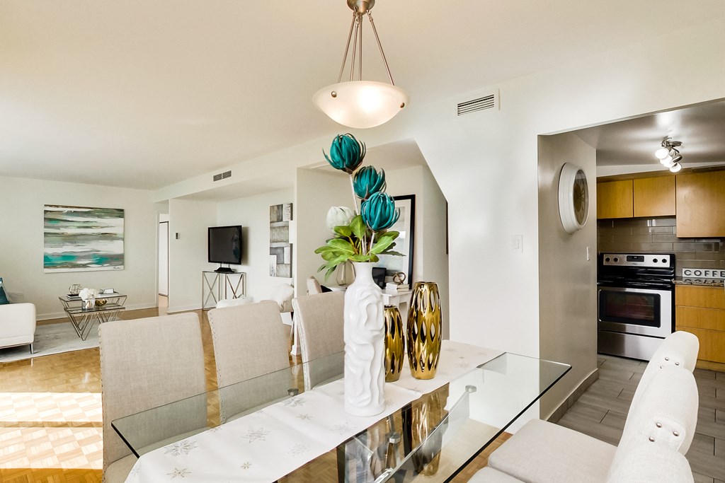 A modern dining room with a glass table and white chairs.