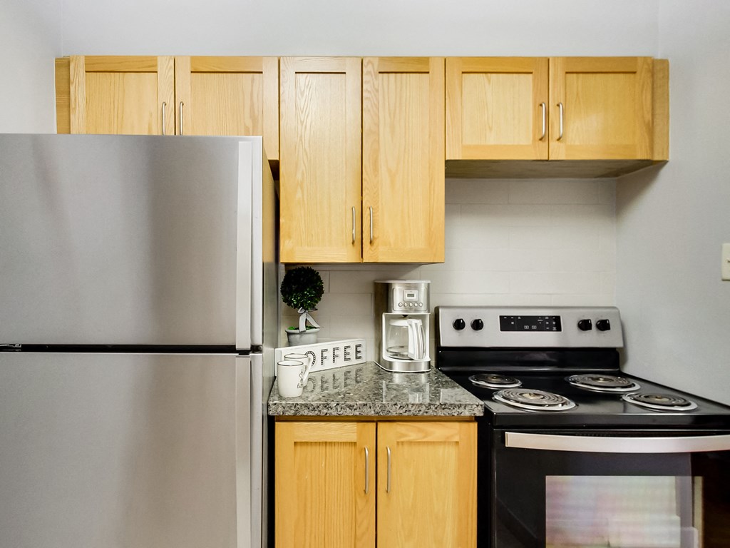 A kitchen with a stove, refrigerator, and cabinets.
