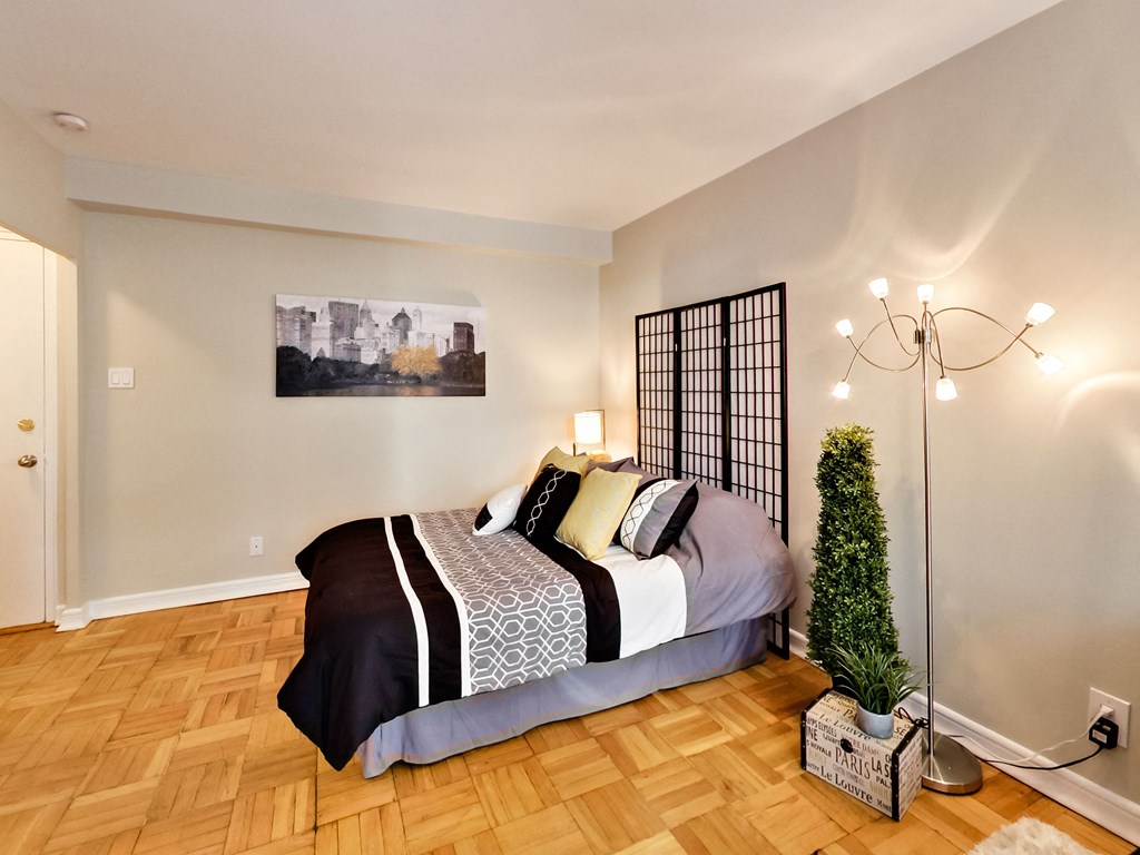 a bedroom with wood floors and a bed with a plant