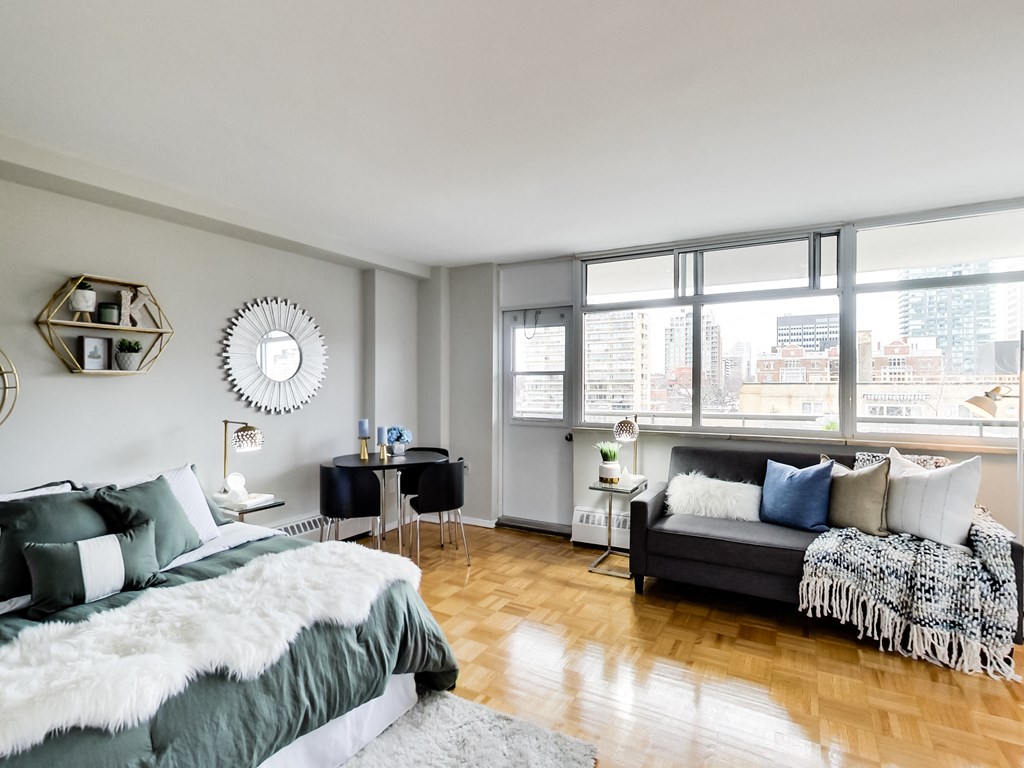 A bedroom with a large bed and a couch with a view of the city.