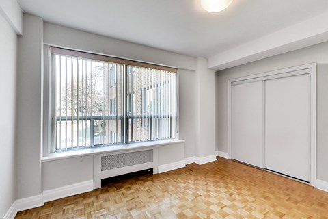 an empty living room with a large window and wood flooring