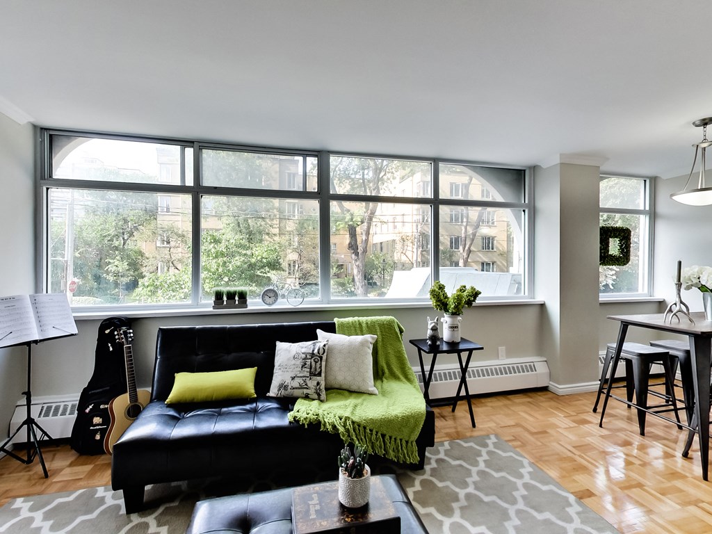 A living room with a black couch and a guitar.