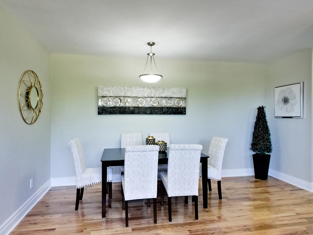 A dining room with a black table and white chairs.