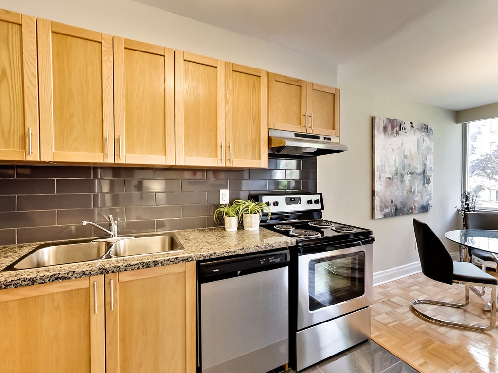 an apartment kitchen with stainless steel appliances and wooden cabinets