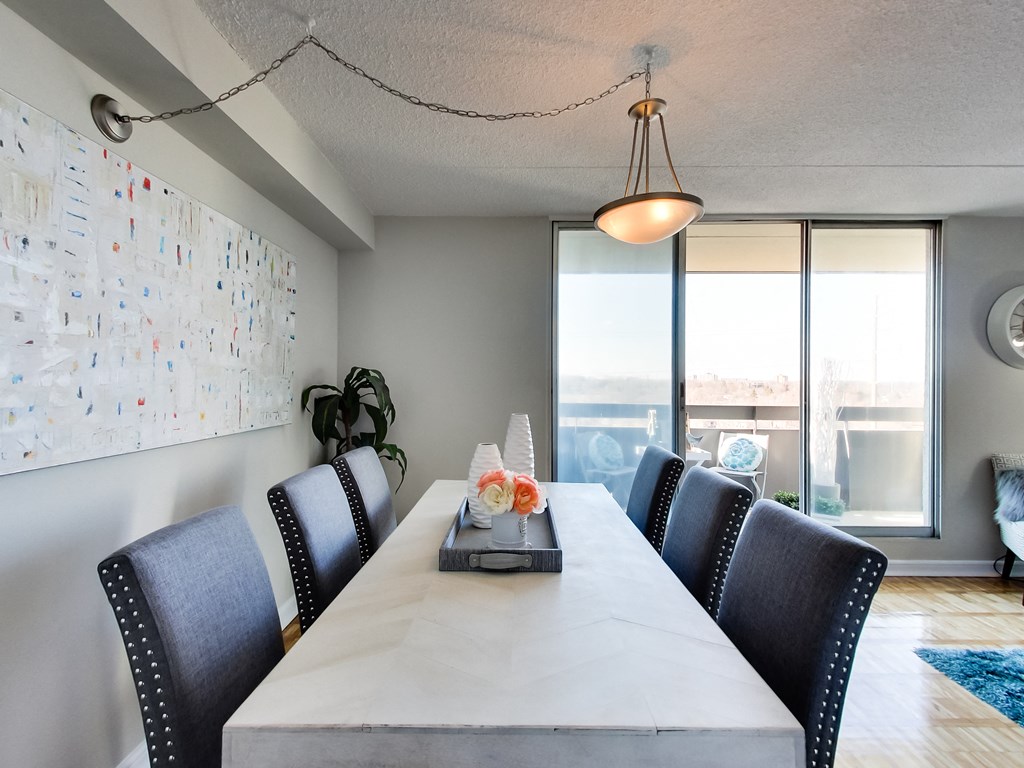 a long dining room table with black chairs and a large window