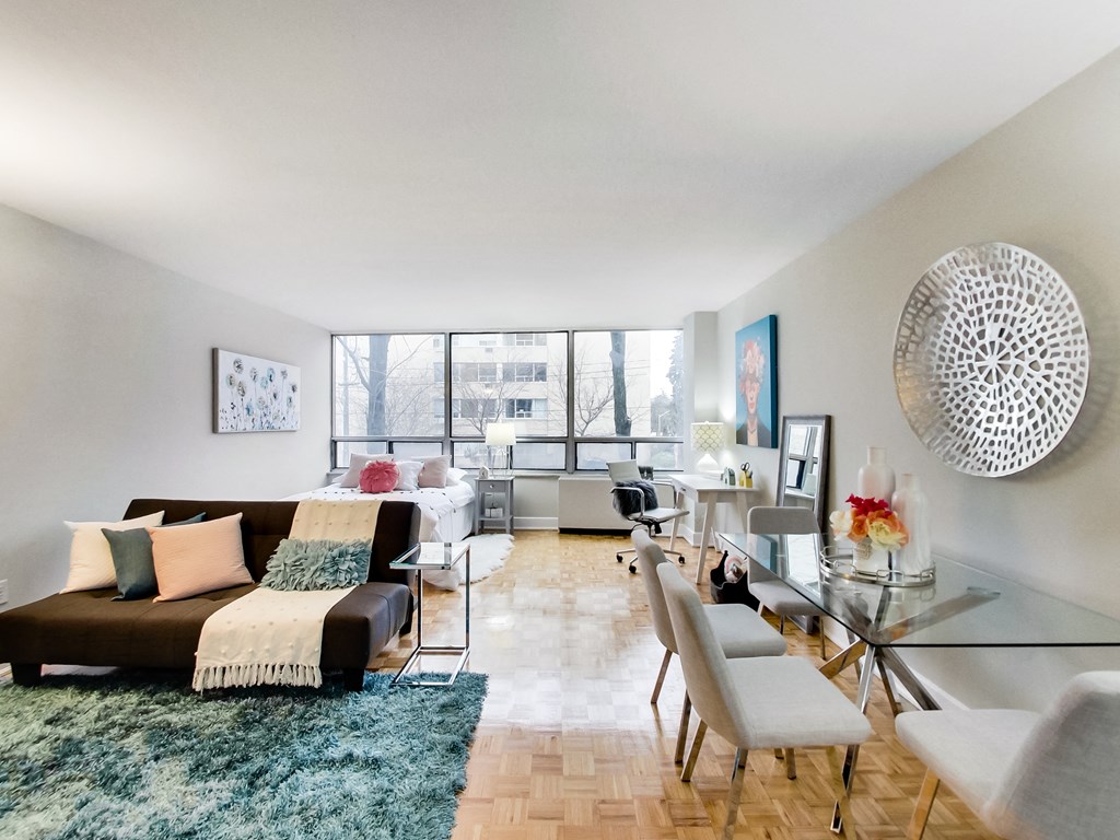 A living room with a brown couch and a glass table.