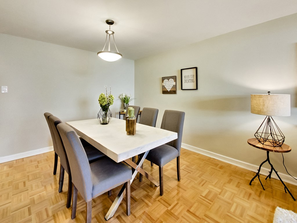 A dining room with a white table and grey chairs.