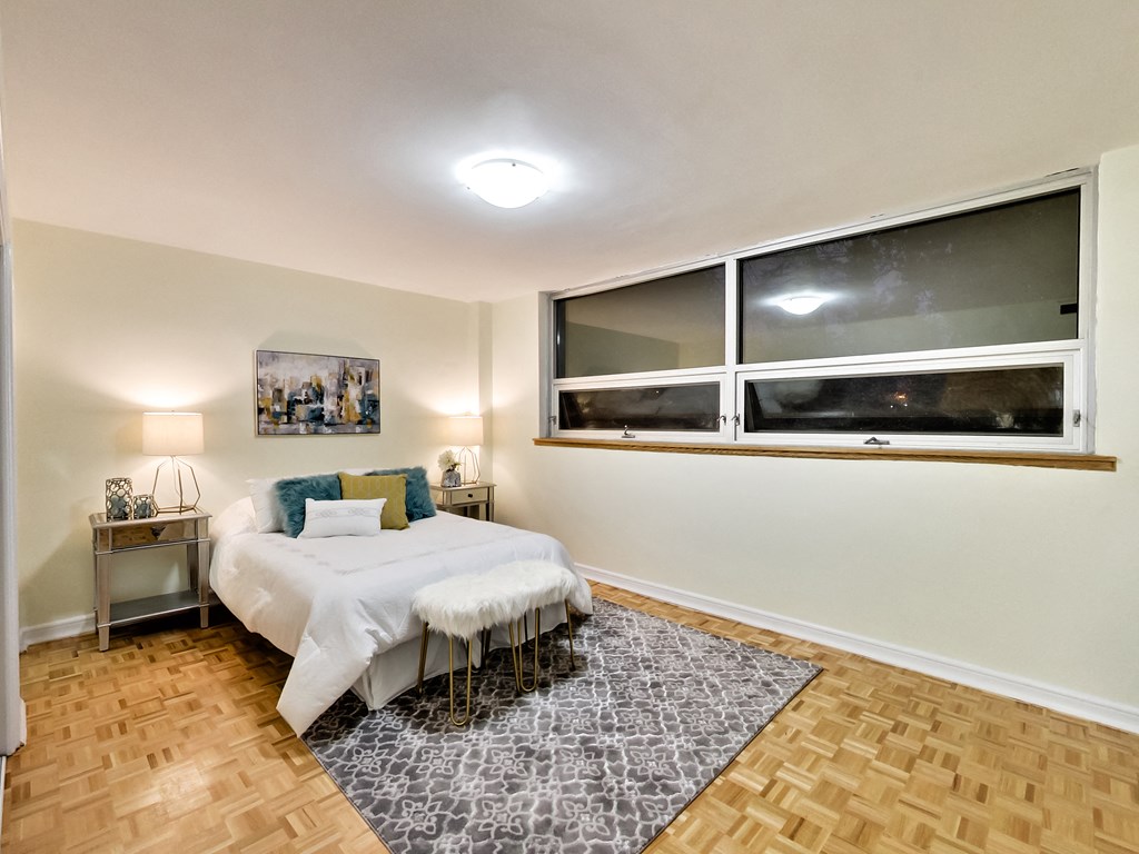 A bedroom with a bed, nightstands, and a window.