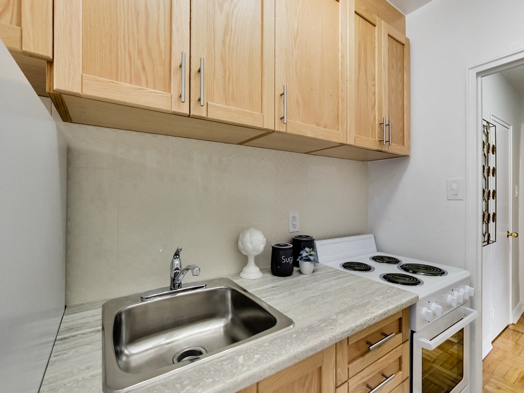 a kitchen with a sink and stove and wooden cabinets