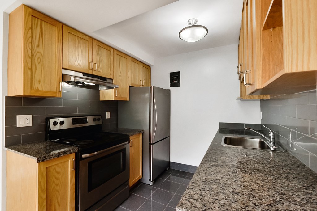 a kitchen with granite countertops and stainless steel appliances and wooden cabinets
