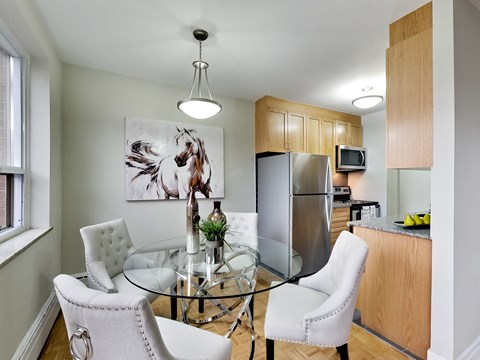 A modern kitchen with a glass table and white chairs.