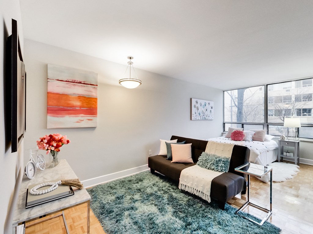 A living room with a couch, a rug, a table, and a painting on the wall.