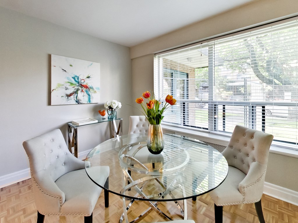 a dining room with a glass table and chairs and a large window