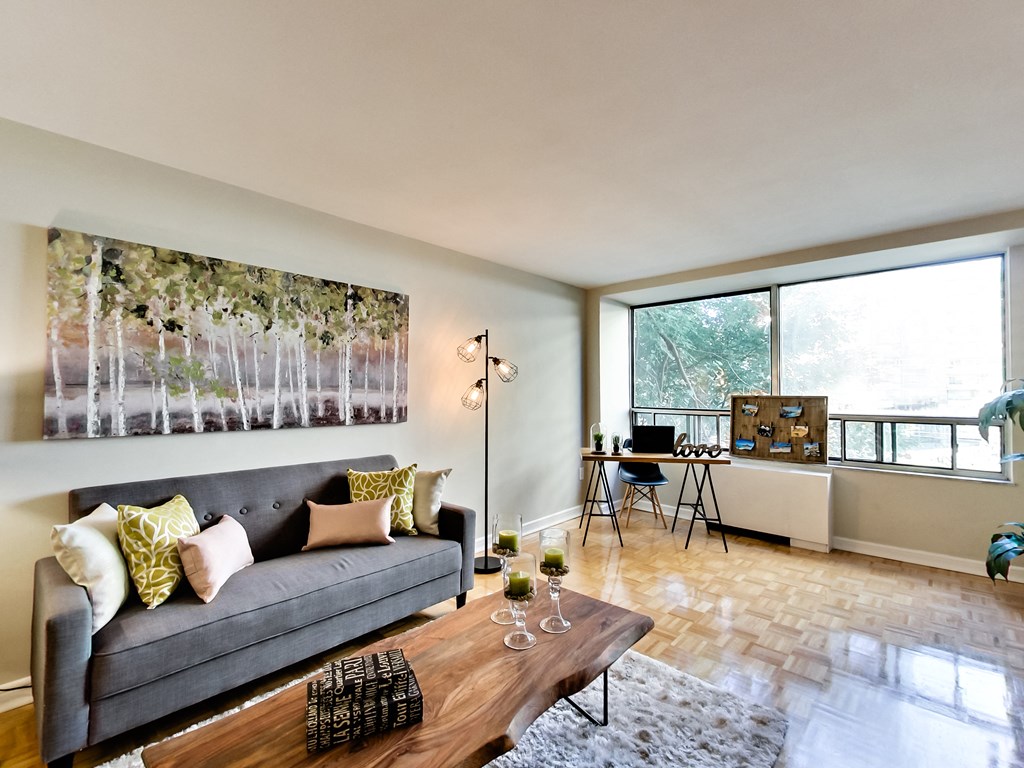 A living room with a grey couch and a painting on the wall.