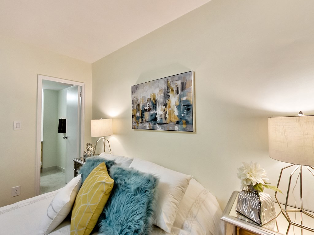 A living room with a white couch and a painting on the wall.