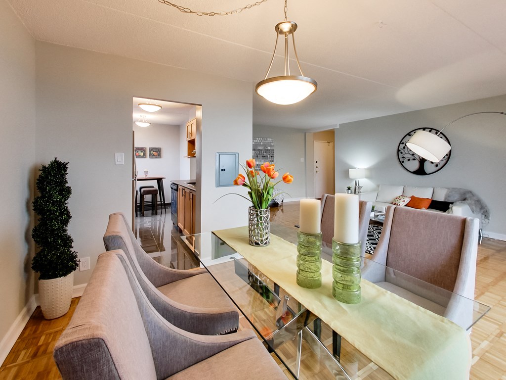a living room with a glass table with chairs and a dining room table with flowers