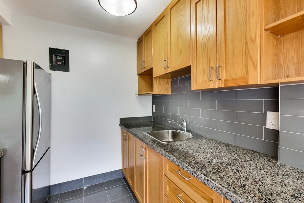 an empty kitchen with granite counter top and stainless steel refrigerator