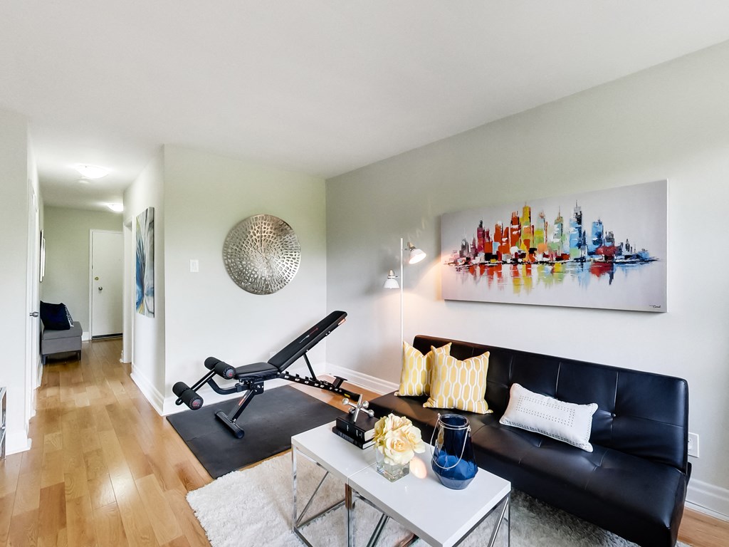 A black leather couch sits in a living room with a white coffee table in front of it.