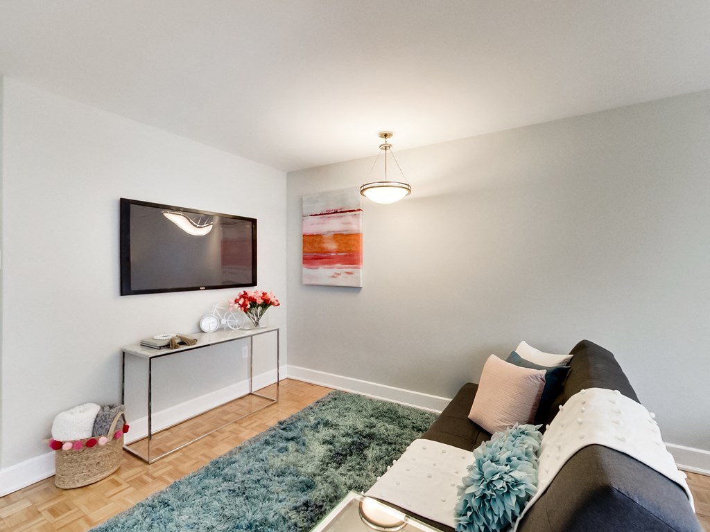 A living room with a grey couch and a television on the wall.