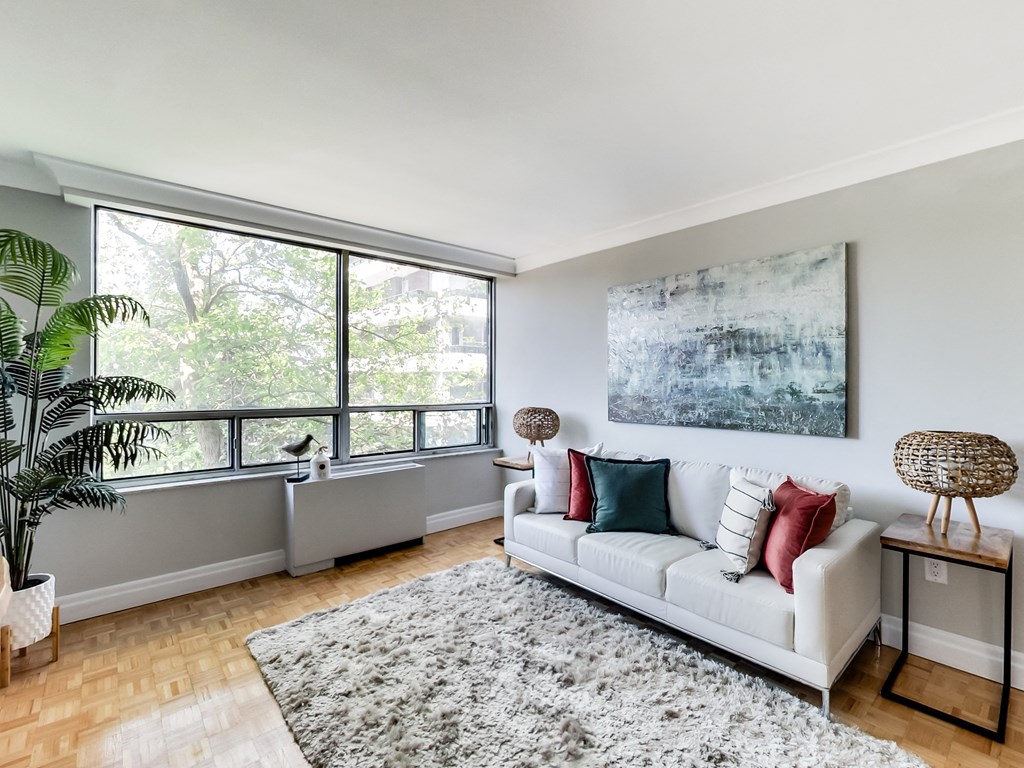 A living room with a white couch and a large painting on the wall.