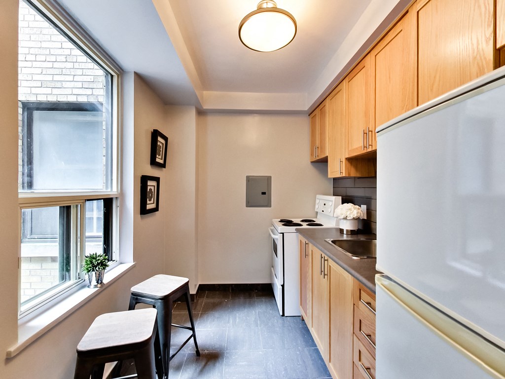 a kitchen with wooden cabinets and a window and a white refrigerator