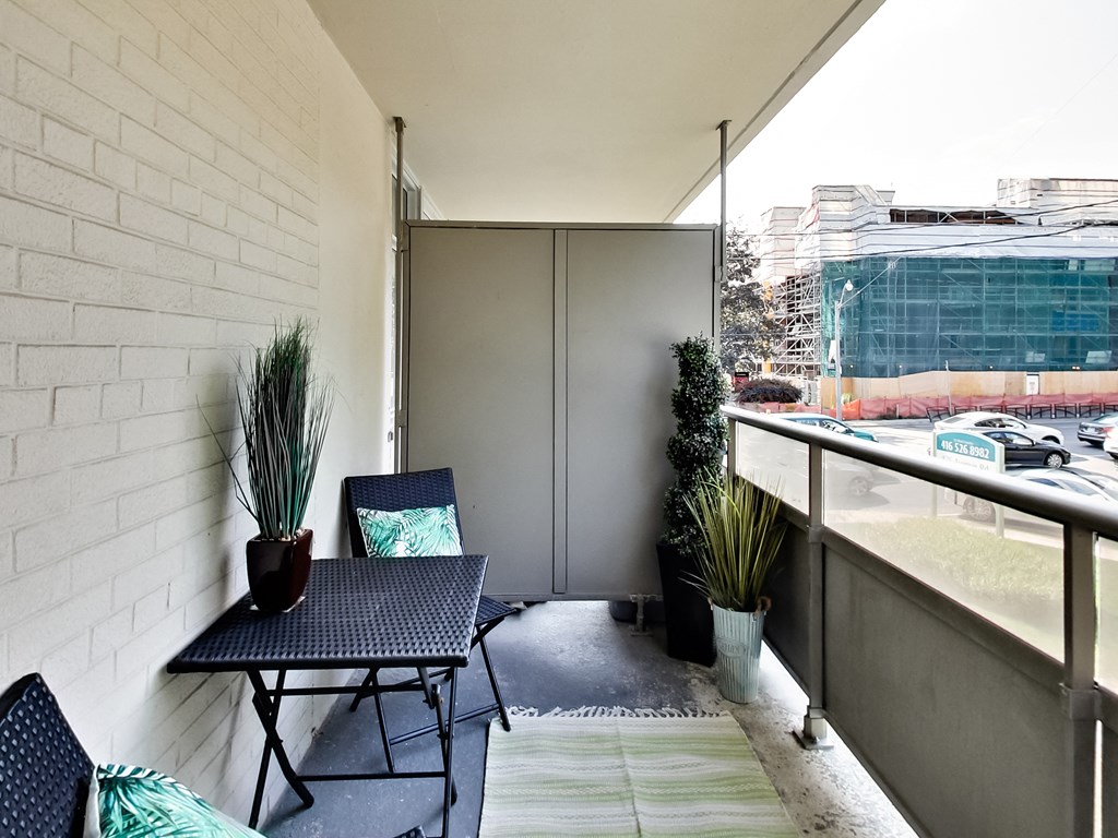 A balcony with a table and chairs overlooking a street.