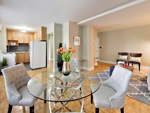 a living room with a glass table and chairs and a kitchen