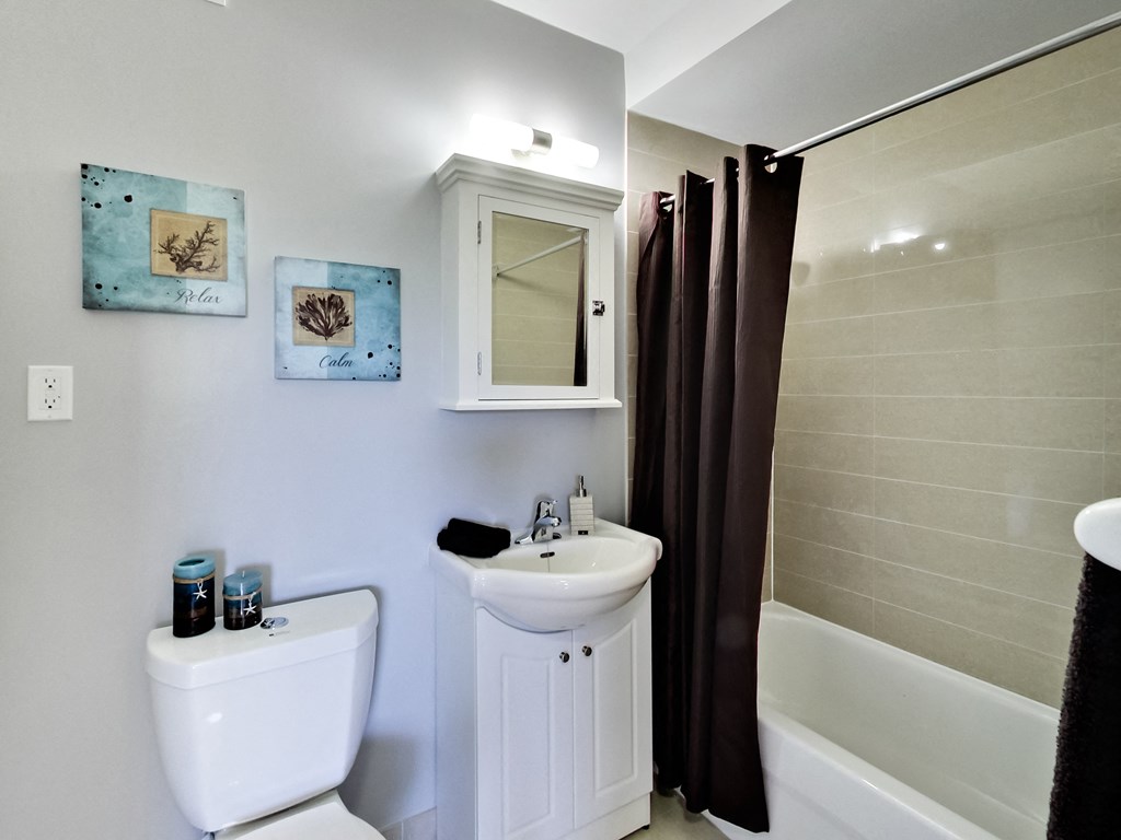 A white toilet sits next to a white sink in a bathroom.