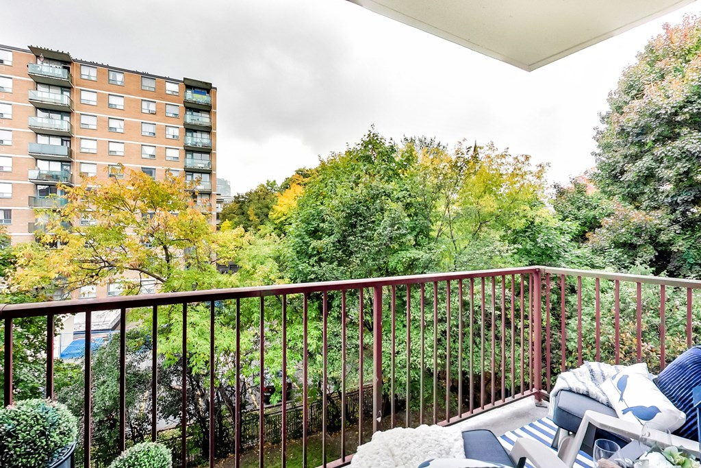 a balcony with a couch and chairs and a view of a garden