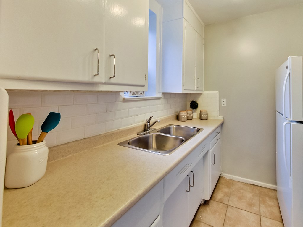 a kitchen with white cabinets and a sink and a refrigerator