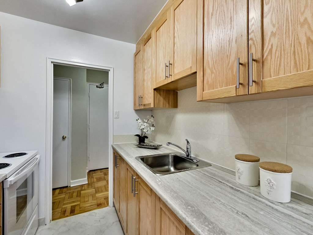 a kitchen with a sink and wooden cabinets and a door to a hallway