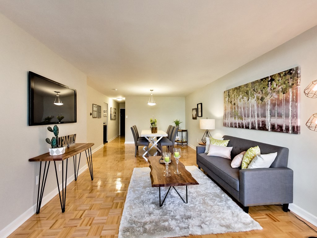 A living room with a grey couch, a coffee table, and a painting on the wall.