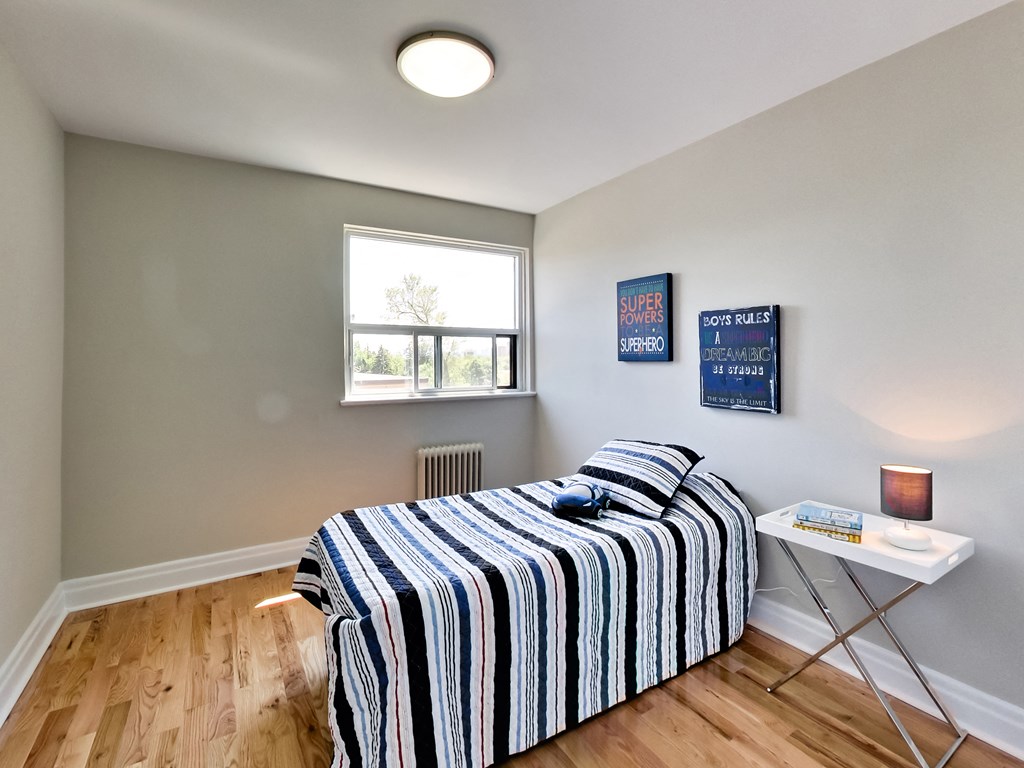 A bedroom with a bed, a small table, and two framed pictures on the wall.